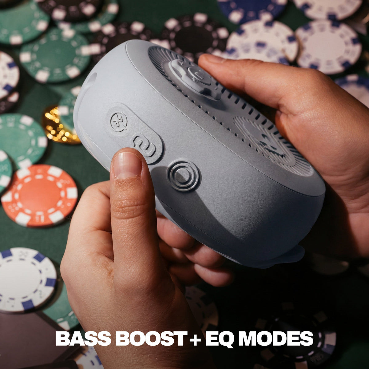 Person holding a gray electronic device with buttons, surrounded by poker chips on a green felt surface. | Cement